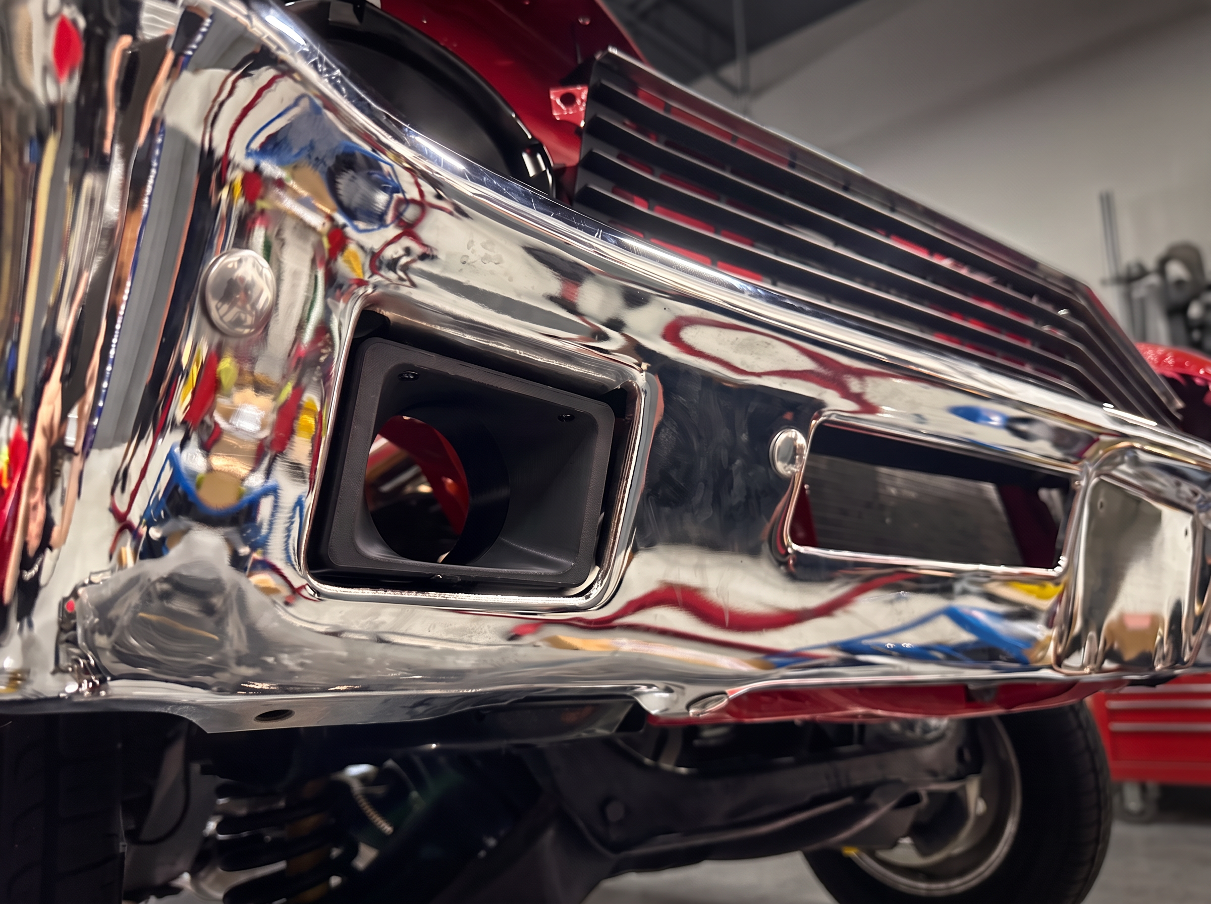 Angled view of the prototype brake cooling duct test-fitted in the Nova chrome bumper, digitally recolored black
